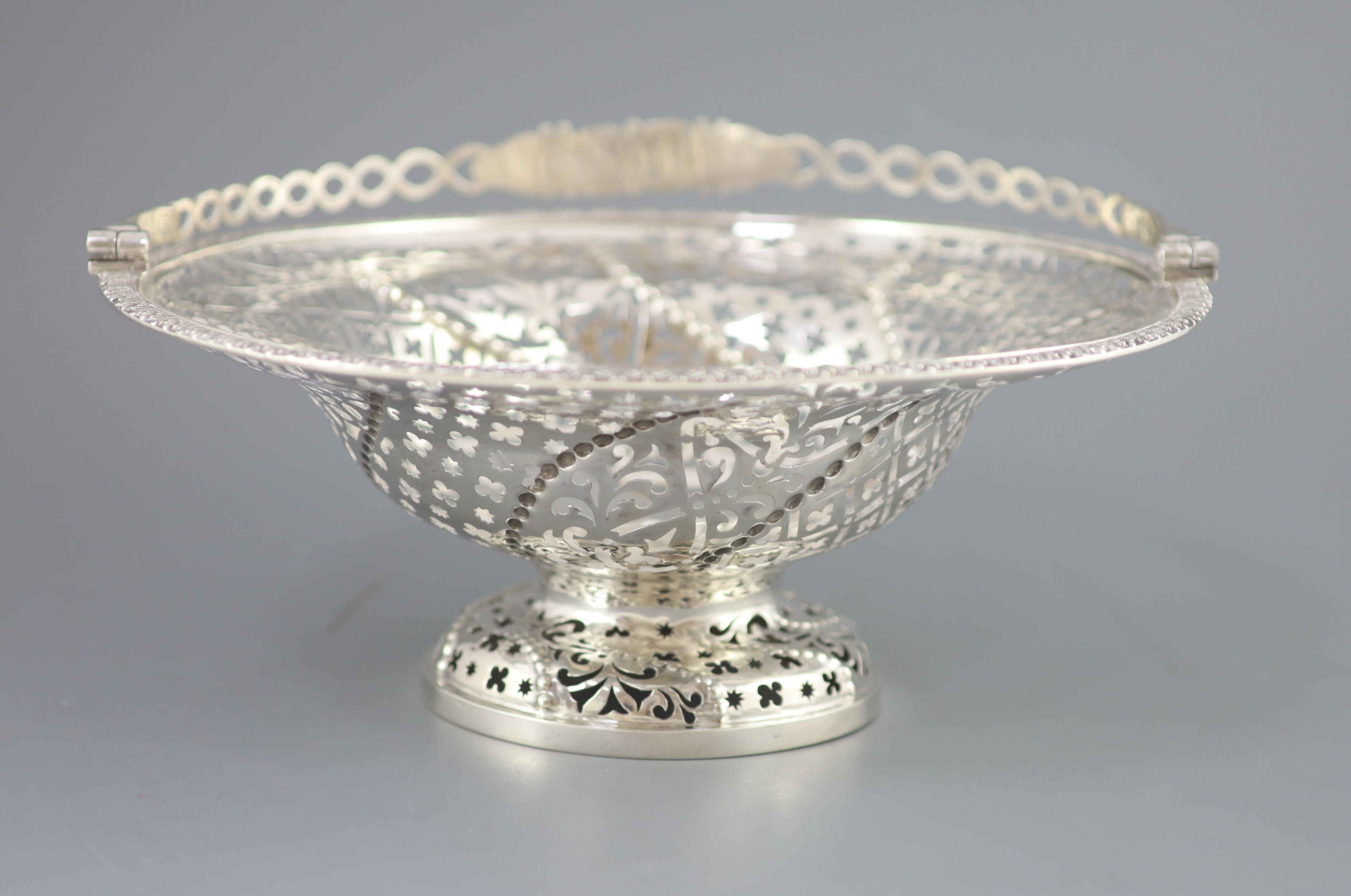 A George III pierced silver pedestal bread basket, with oval ring swing handle,